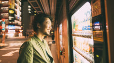 young japanese man buys drink from the machine image