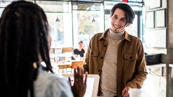 young man using credit card reader at coffee shop counter